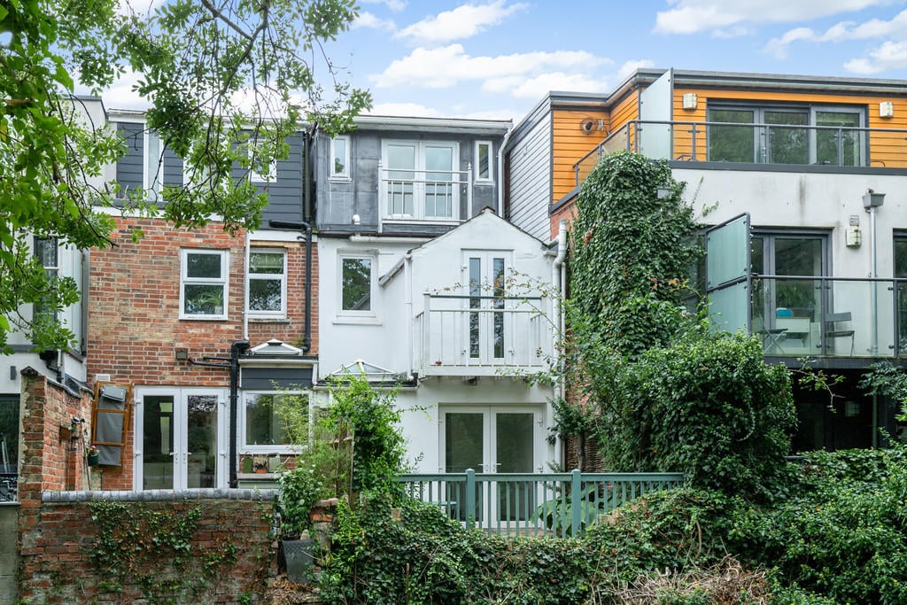 Dudley Gardens, St. Clements OX4 - view of the back of terraced houses in Oxford with leafy tree branches bordering top left and vines growing the rightmost house website image